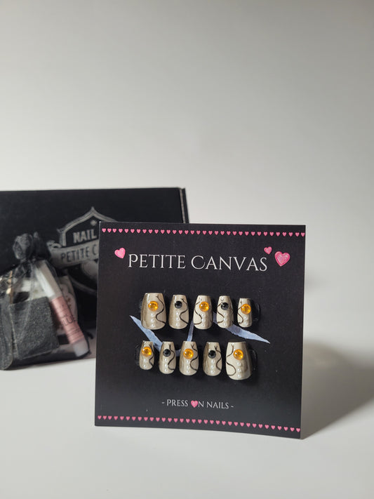 L'Oeil du Serpent press-on nail set — nude short coffin nails with delicate black lines, pearls and amber eyes, handmade by Petite Canvas