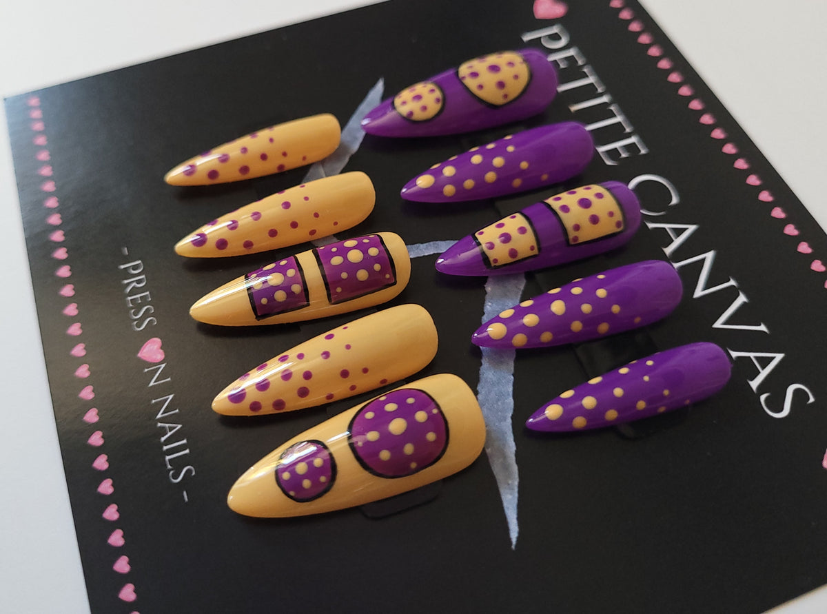 Close-up of Polka Anti-dote long stiletto press-on nails — purple and mustard polka dots with a venomous twist