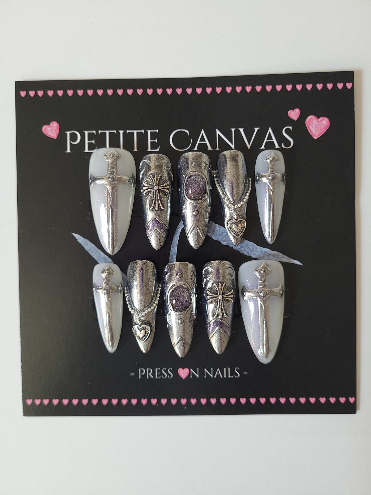 Snow Queen press-on nails detail — polished silver chrome with miniature swords and purple cat-eye shimmer